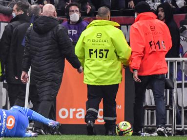 Pemain Olympique de Marseille Dimitri Payet jatuh setelah terkena botol air yang dilemparkan oleh seorang suporter, di Stadion Groupama, Lyon, Prancis, Minggu (21/11/2021). (AFP/Philippe Desmazes)