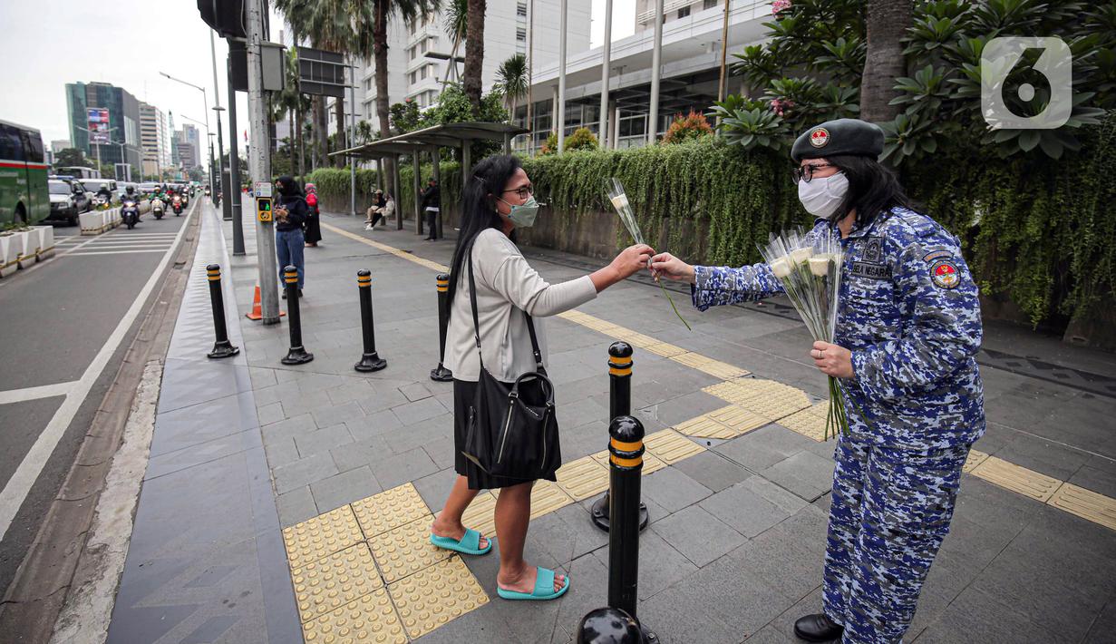 Perserta yang tergabung dalam Forum Kader Bela Negara DKI Jakarta membagikan bunga dan masker kepada pejalan kaki di Jalan Thamrin, Jakarta, Rabu (22/12/2021). Aksi tersebut merupakan bentuk apresiasi terhadap kaum perempuan terutama pada peringatan Hari Ibu. (Liputan6.com/Faizal Fanani)