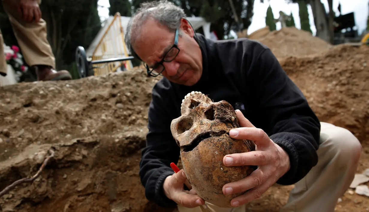 Arkeolog menunjukkan tengkorak saat penggalian kuburan massal korban Perang Saudara Spanyol di El Carmen, Valladolid, (9/5). Penggalian ini dimulai sejak 2014 dan diharapkan selesai tahun ini. (REUTERS/Juan Medina)