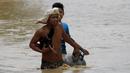 Seorang warga tampak membawa tabung gas dan hewan peliharaanya melewati jalanan yang banjir pasca bencana badai topan Koppu di Nueva Ecija,  Filipina, Senin (19/10/2015). Badai terjadi pada Minggu pagi waktu setempat. (REUTERS/Erik De Castro)