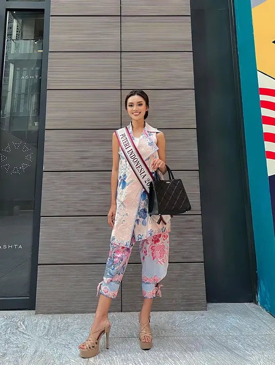 Puteri Indonesia 2023 Farhana Nariswari tampil cantik mengenakan batik bersiluet modern. Inner putih ditumpuk dengan outer batik berkerah tanpa lengan bernuansa merah muda yang lembut, dikombinasikan dengan midi pants dengan pita di bagian bawah. [Foto: Instagram/farhanariswari]