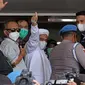 Rizieq Shihab (tengah) melambaikan tangan sesaat sebelum masuk gedung utama Mapolda Metro Jaya, Jakarta, Sabtu (12/12/2020). Rizieq Shihab akan menjalani pemeriksan sebagai tersangka penghasutan dan kerumunan di tengah pandemi Covid-19. (Liputan6.com/Helmi Fithriansyah)