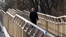 Seorang warga yang mengenakan masker berjalan di jembatan, Beijing, China, Kamis (15/12/2022). Seminggu setelah China melonggarkan beberapa tindakan pengendalian COVID-19 yang paling ketat di dunia, ketidakpastian masih ada mengenai arah pandemi di negara dengan jumlah penduduk terpadat di dunia tersebut. (AP Photo/Ng Han Guan)