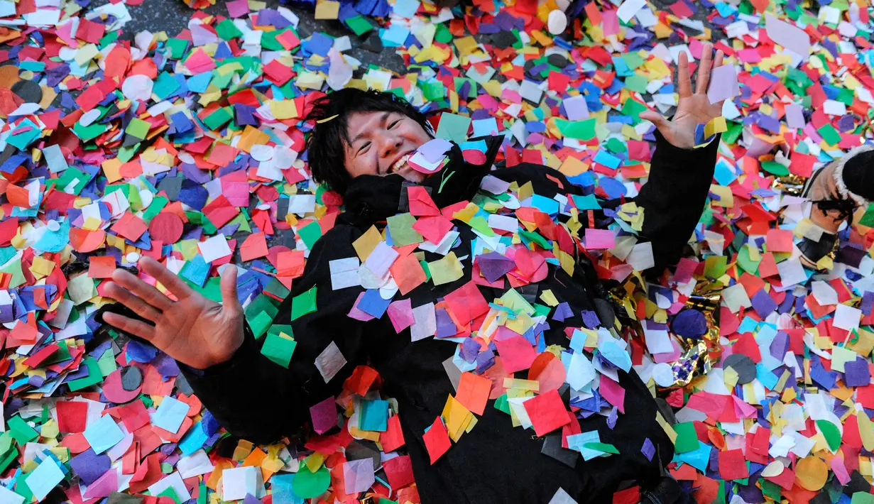 Seorang pria berbaring diantara confetti saat perayaan tahun baru di Times Square, New York, AS (1/1). Selain tu juga New York City punya tradisi menjatuhkan bola saat malam pergantian tahun. (Reuters/Stephanie Keith)