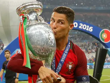 Cristiano Ronaldo menciumi Piala Eropa 2016 usai memenangkan laga melawan Prancis di Stade de France, Senin (11/7). Portugal menang dengan skor tipis 1-0. (REUTERS)