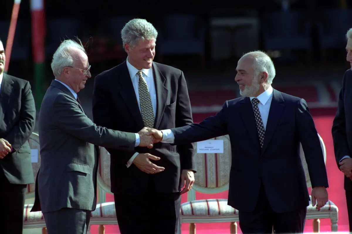 PM Israel Yitzhak Rabin (kiri) bersalaman dengan Raja Hussein dari Yordania (kanan) usai menyepakati perdamaian kedua negara, dimediasi oleh Presiden AS Bill Clinton (tengah) pada 26 Oktober 2020 (Government Press Office Israel)