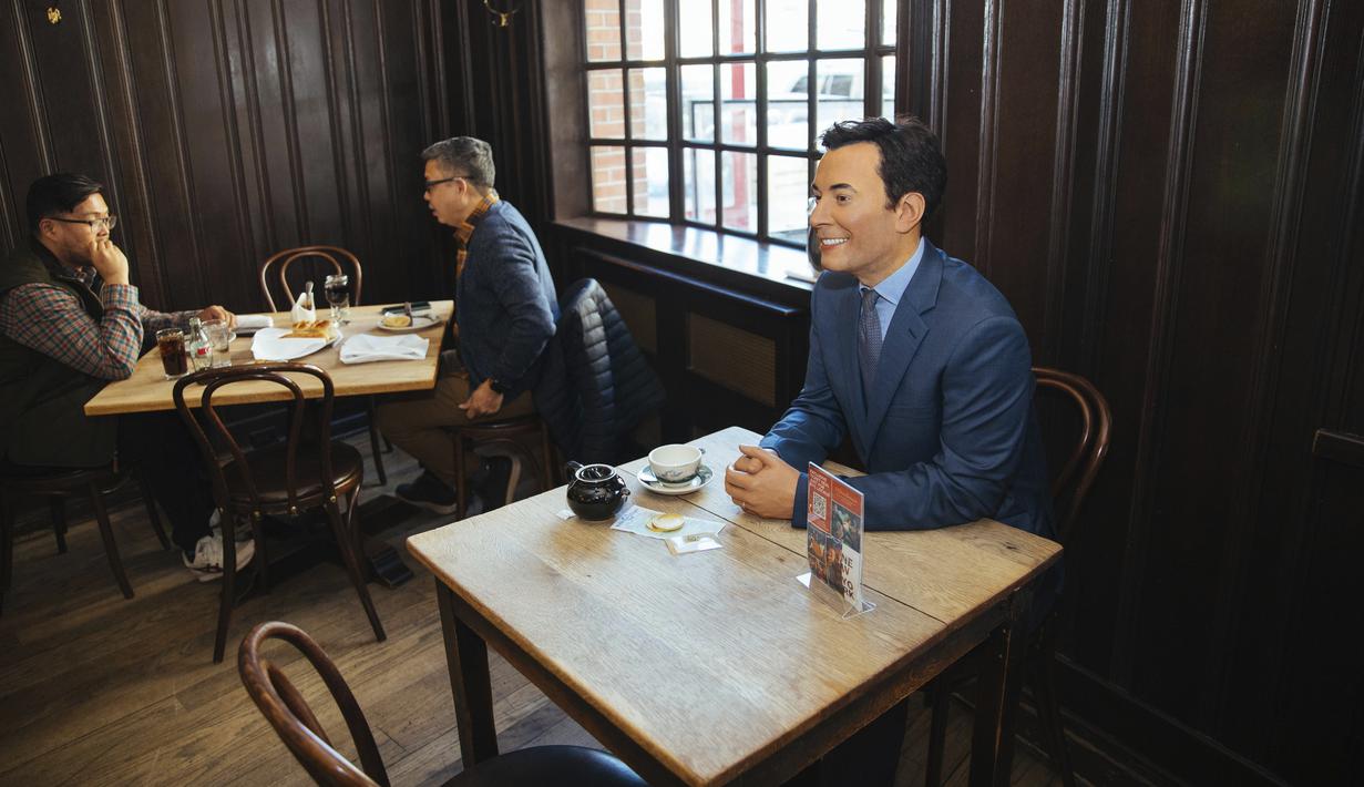 Patung lilin komedian Jimmy Fallon menempati meja di Peter Luger Steakhouse di New York, Jumat (26/2/2021). Patung yang dipinjam dari Madame Tussauds itu membantu mengisi meja kosong yang tidak digunakan selama pelonggaran pembatasan aturan COVID-19 makan di dalam ruangan.  (AP Photo/Kevin Hagen)
