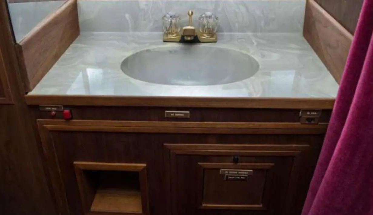 Wastafel yang berada dalam jet pribadi yang pernah dimiliki oleh Elvis Presley yang berada di landasan pacu di New Mexico, AS. Interior pesawat ini di desain dengan warna emas, ornamen kayu dan jok beludru merah. (GWS Auctions, Inc. via AP)