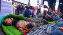 Seorang pria memeluk seekor anjing saat para aktivis mengadakan "tidur bersama" untuk meningkatkan kesadaran akan Bulan Kesadaran Tunawisma Pemuda, di Times Square, New York City, pada 16 November 2023. (KENA BETANCUR/AFP)