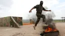 Seorang pejuang Jaysh al-Izza (the Army of Glory) melompati api saat melakukan latihan di kota Idlib, Suriah (9/4). Pejuang Jaysh al-Izza ini adalah afiliasi dari tentara Suriah yang didukung oleh Turki. (AFP/Omar Haj Kadour)