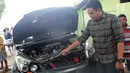 Seorang pria menunjukkan mobil yang rusak usai tertimpa pohon berumur puluhan tahun di Jalan Trans Sulawesi, Limboto, Gorontalo, Senin, (21/1). Tidak ada korban jiwa dalam kejadian tersebut. (Liputan6.com/Arfandi Ibrahim)