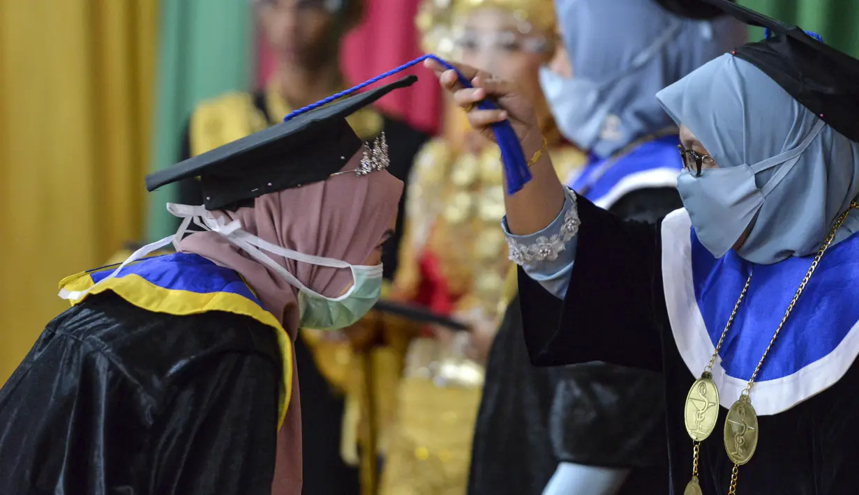 Seorang siswa yang mengenakan masker dan pelindung sebagai tindakan pencegahan terhadap virus Corona COVID-19 mengikuti acara wisuda SMK Farmasi di Banda Aceh (24/9/2020). (AFP/Chaideer Mahyuddin)