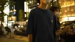 Seorang pria dan seorang wanita mengenakan masker berjalan di sepanjang jalan di distrik perbelanjaan Ginza Tokyo, Kamis (23/9/2021). Ginza dikenal sebagai salah satu pusat perbelanjaan paling mewah di dunia. (AP Photo/Hiro Komae)