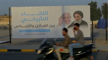 Sebuah papan reklame yang menampilkan gambar Paus Fransiskus dan ulama terkemuka Irak Ayatollah Ali al-Sistani, di Najaf, Irak, Kamis (4/3/2021). Pemimpin Tertinggi Umat Katolik Paus Fransiskus akan melakukan perjalanan bersejarah ke Irak pada Jumat (5/3/2021) waktu setempat. (AP Photo/Anmar Khalil)