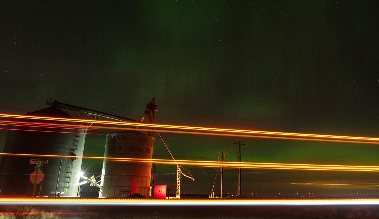 Cahaya dari semi-truk yang lewat di State Route 26 terlacak dalam paparan kamera berwaktu sebagai aurora borealis, juga dikenal sebagai cahaya utara, terlihat pada langit malam di samping elevator biji-bijian dekat Washtucna, Washington, Amerika Serikat, 26 Februari 2023. Peramal cuaca luar angkasa memperkirakan bahwa aktivitas akan berlanjut Senin malam di sebagian Amerika Serikat dan Eropa. (AP Photo/Ted S. Warren)