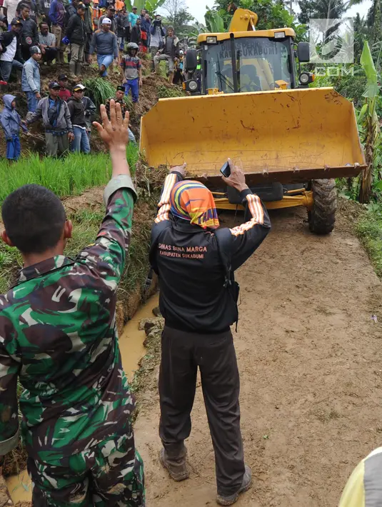 Warga memandu alat berat melalui jalan kecil menuju lokasi longsor di Dusun Cimapag, Sirnaresmi, Cisolok, Sukabumi, Jawa Barat, Selasa (1/1). Korban meninggal longsor Sukabumi bertambah menjadi lima orang. (Merdeka.com/Arie Basuki)