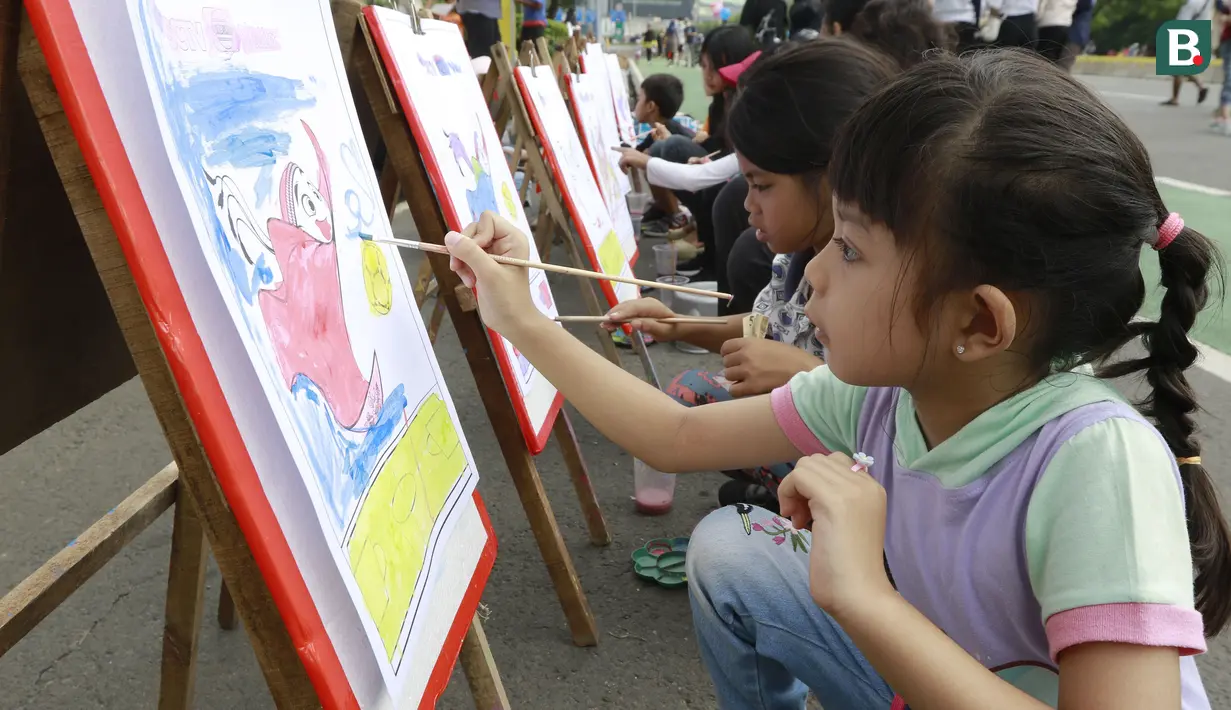 Sejumlah anak asyik melukis maskot Piala Dunia 2022, La'eeb, saat Car Free Day (CFD) di kawasan Sudirman, Jakarta, Minggu (06/11/2022). (Bola.com/M iqbal Ichsan)