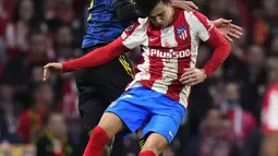 Bek Manchester United, Raphael Varane berebut bola dengan penyerang Atletico Madrid, Joao Felix pada pertandingan leg pertama babak 16 besar Liga Champions di Stadion Wanda Metropolitano, Kamis (24/2/2022). Atletico bermain imbang atas Manchester United 1-1. (AP Foto/Manu Fernandez)
