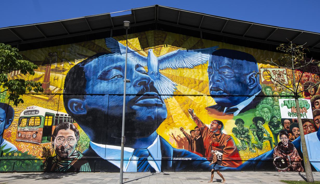 Seorang pria melewati mural Sonhos de Liberdade yang dibuat seniman Acme, yang menghormati para pemimpin perjuangan untuk kesetaraan ras, di distrik seni Porto di Rio de Janeiro, 17 November 2021. Brasil menyambut Hari Kesadaran Kulit Hitam yang diperingati setiap 20 November. (AP Photo/Bruna Prado)