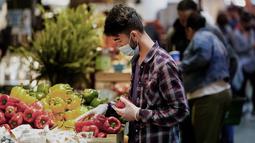 Serang pedagang yang mengenakan masker menata dagangannya di Reading Terminal Market di Philadelphia, Jumat (22/4/2022). Kota itu meninggalkan mandat masker dalam ruangan pada hari Jumat, hanya beberapa hari setelah menjadi kota metropolitan AS pertama yang menerapkan kembali wajib masker sebagai tanggoapan atas peningkatan kasus COVID-19 dan rawat inap. (AP Photo/Matt Rourke)