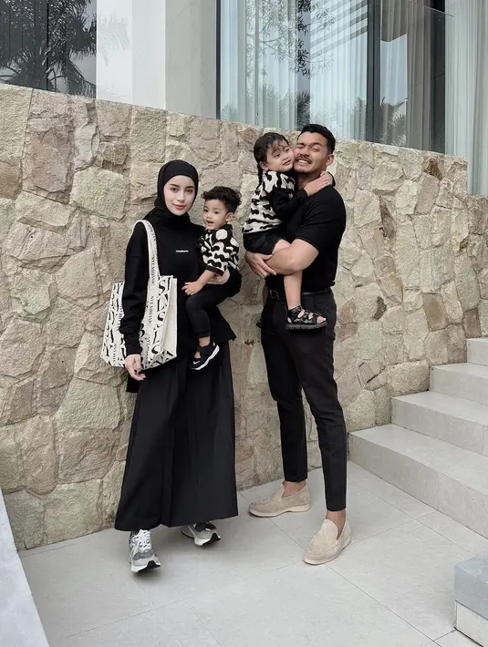 Potret manis keluarga kecil Aghnia Punjabi. Ia dan sang suami kompak mengenakan outfit serba hitam, sedangkan dua anaknya mengenakan baju kembar, yaitu atasan bermotif abstrak hitam-putih dan bawahan, serta sandal berwarna hitam. [Foto: Instagram/emyaghnia]