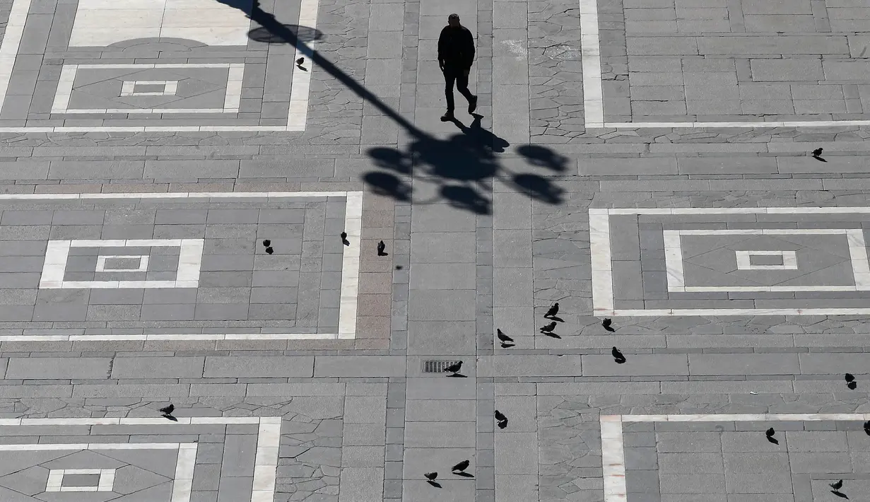 Seorang pria berjalan di Alun-Alun Duomo, Milan, Italia, Minggu (8/3/2020). Italia menutup seluruh wilayahnya dari 10 Maret 2020 sampai 3 April 2020 demi menekan penyebaran virus corona (COVID-19). (AP Photo/Antonio Calanni)