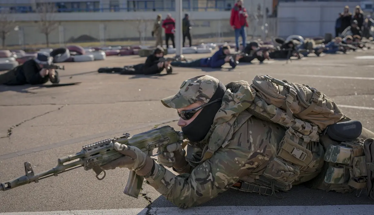 Seorang anggota Unit Pasukan Khusus Azov, dari Garda Nasional Ukraina, menunjukkan posisi menembak selama latihan dasar perang untuk warga sipil di Mariupol, wilayah Donetsk, Minggu (13/2/2022). Mereka disiapkan untuk bisa bertahan di tengah kekhawatiran akan invasi Rusia. (AP Photo/Vadim Ghirda)