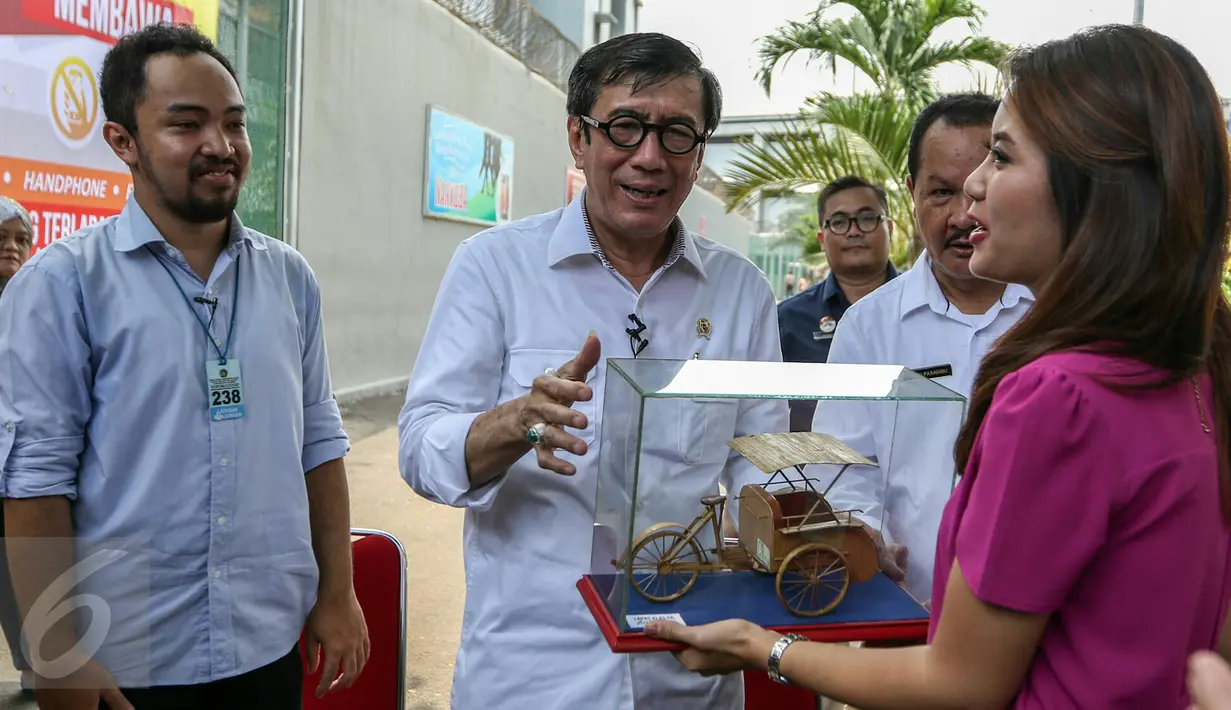 Menteri Hukum dan HAM, Yasonna Laoly memberikan cinderamata buatan penghuni lapas Salemba kepada Liputan6 SCTV, Jakarta, Rabu (9/3/2016). Kunjungan Menkumham tersebut untuk mengontrol peredaran narkotika di dalam Lapas. (Liputan6.com/Yoppy Renato)
