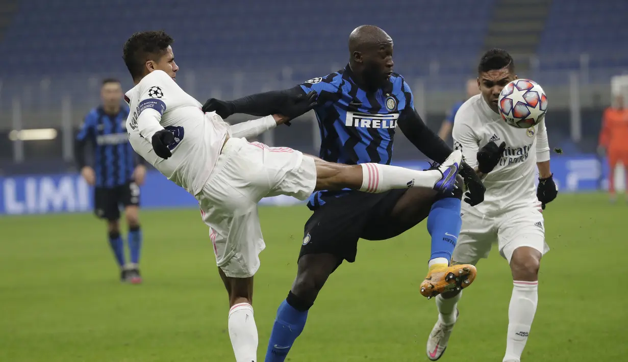Bek Real Madrid, Raphael Varane, berebut bola dengan penyerang Inter Milan, Romelu Lukaku, pada laga lanjutan Liga Champions di Giuseppe Meazza, Kamis (26/11/2020) dini hari WIB. Real Madrid menang 2-0 atas Inter Milan. (AP Photo/Luca Bruno)