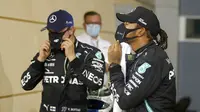 Pembalap Mercedes Lewis Hamilton (kanan), dan pembalap Mercedes Valtteri Bottas memakai masker usai sesi kualifikasi di Formula 1 Sirkuit Internasional Bahrain di Sakhir, Bahrain, Sabtu (28/11/2020). Lewis Hamilton dinyatakan positif COVID-19. (Hamad Mohammed, Pool via AP, File)