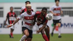 Pemain Madura United, Rafael Feital Da Silva (kiri) dan pemain Persipura Jayapura, Donni Monim berebut bola dalam laga pekan ke-6 BRI Liga 1 2021/2022 di Stadion Wibawa Mukti, Cikarang, Minggu (03/10/2021). (Bola.com/Bagaskara Lazuardi)