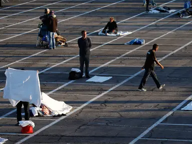 Orang-orang bersiap tidur di tempat-tempat yang ditandai dengan kotak-kotak yang diberi jarak untuk social distancing di lahan parkir di Las Vegas, Senin (30/3/2020). Tempat parkir itu diubah menjadi tempat penampungan sementara untuk para tunawisma di ttengah pandemi Covid-19. (AP/John Locher)