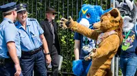 Peserta mengenakan kostum binatang mengajak polisi untuk berpelukan saat parade konvensi Eurofurence di Berlin, Jerman (17/8). Dalam acara peserta mengenakan kostum hewan berbulu. (AFP Photo/Ganjil Andersen)