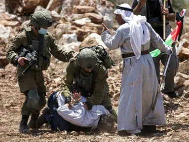 Tentara Israel membekuk pengunjuk rasa Palestina di dekat Desa Shoufah, wilayah Tepi Barat yang diduduki Israel (20/8/2020). Tentara Israel menangkap pengunjuk rasa yang kembali beraksi menentang pembukaan lahan sebagai bagian dari proyek permukiman Israel di wilayahnya. (AFP/JAAFAR ASHTIYEH)