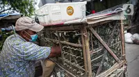 Pedagang mengambil burung pipit dalam kandang di kawasan Pasar Petak Sembilan, Glodok, Jakarta, Minggu (31/1/2021). Pedagang pipit mengaku mengalami penurunan omzet saat pandemi karena banyak vihara yang tak menyelenggarakan ibadah untuk mengurangi penyebaran COVID-19. (Liputan6.com/Faizal Fanani)