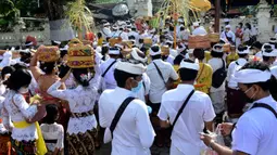 Umat Hindu membawa sesaji saat akan berdoa pada perayaan Hari Raya Kuningan di Pura Sakenan, Pulau Serangan, Denpasar, Bali, Sabtu (20/11/2021). Kuningan merupakan hari terakhir perayaan Galungan yang diyakini sebagai hari naiknya roh suci leluhur kembali ke surga. (Sonny TUMBELAKA/AFP)