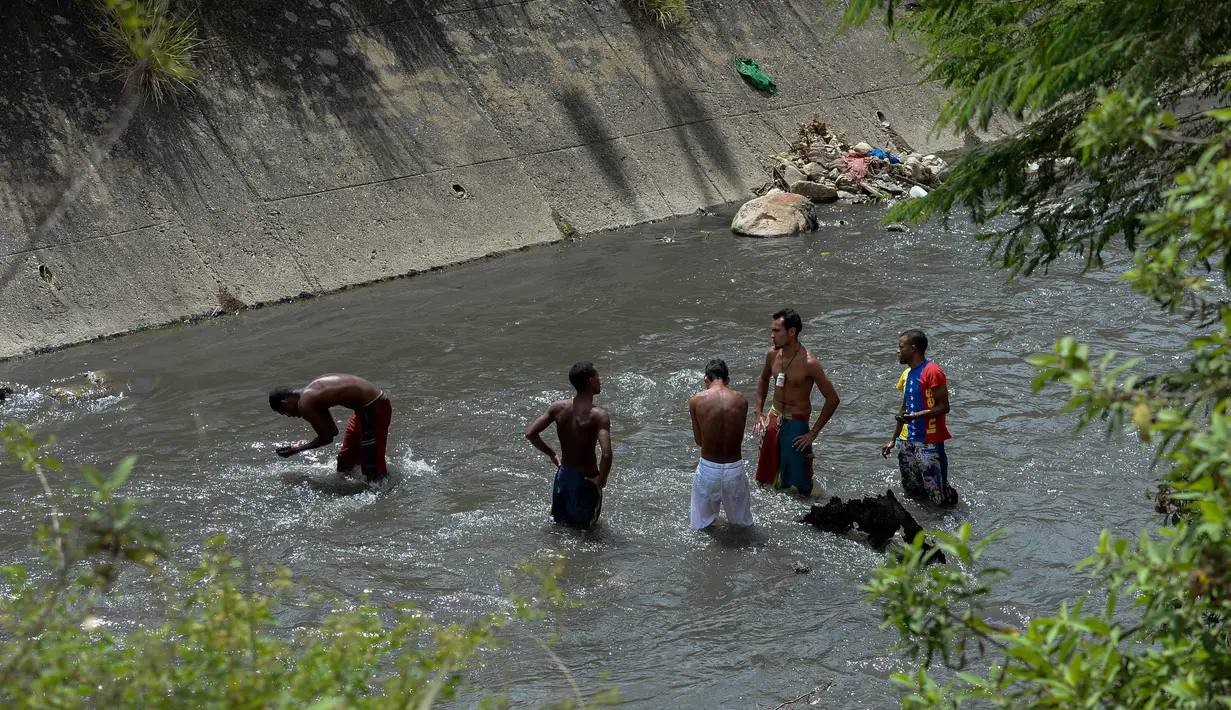 Sejumlah pria mencari logam berharga di Sungai Guaire, di Caracas, Venezuela (1/2). Puluhan warga mencari logam atau tembaga setiap hari di Sungai Guaire, tempat selokan Caracas mengalir.  (AFP Photo/Federico Parra)