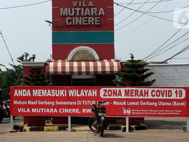Pengendara motor melintas di depan gerbang utama perumahan Villa Mutiara Cinere, Depok, Jawa Barat, Jumat (16/7/21). Sebanyak 100 orang warga di perumahan Villa Mutiara Cinere terkonfirmasi positif Covid-19. (Liputan6.com/Johan Tallo)