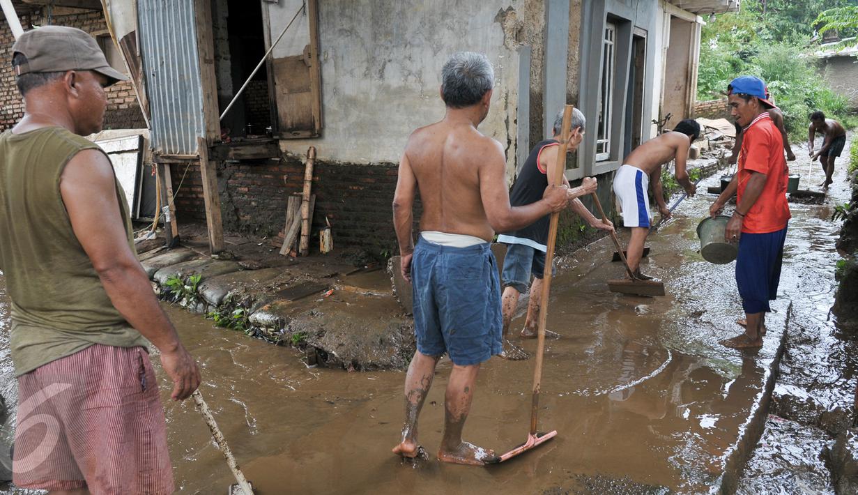 Warga bergotong royong membersihkan lumpur sisa banjir yang menutup jalan, Jakarta, Senin (7/11). Sebelumnya, ratusan rumah warga di RW 02 Cawang, Kramat Jati, Jakarta Timur tergenang akibat banjir kiriman dari kawasan Bogor. (Liputan6.com/Yoppy Renato)
