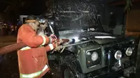 Petugas PMK berupaya memadamkan api yang membakar Land Rover 1961 milik mantan Wabup Tulungagung (Liputan6.com/Zainul Arifin)