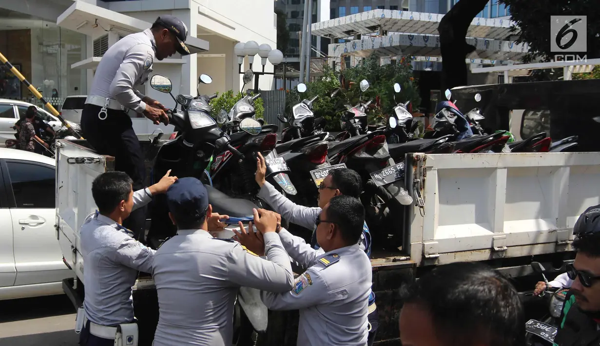 Petugas Dishub DKI Jakarta mengangkut motor saat razia parkir liar di Jalan KH Wahid Hasyim, Jakarta, Rabu (4/4). Dishub DKI Jakarta menertibkan pengendara ojek online yang memarkirkan kendaraan sembarangan di pinggir jalan. (Liputan6.com/Arya Manggala)