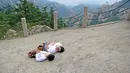 Gao Zhiyu (kiri) dan Chen Zhou merebahkan dirinya saat sampai di puncak gunung di Qingdao, Tiongkok, Selasa (13/9). Keduanya tak memiliki kaki dan menggunakan balok kayu untuk mendaki gunung setinggi 1130 meter. (REUTERS)