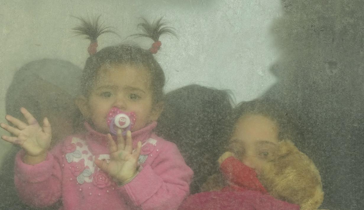 Anak-anak pengungsi melihat keluar dari bus yang berangkat ke Rumania setelah melarikan diri dari perang Ukraina, di persimpangan perbatasan di Palanca, Moldova, pada Jumat (11/3/2022). Invasi Rusia ke Ukraina sudah memasuki hari ke-16 pada hari Jumat ini. (AP Photo/Sergei Grits)