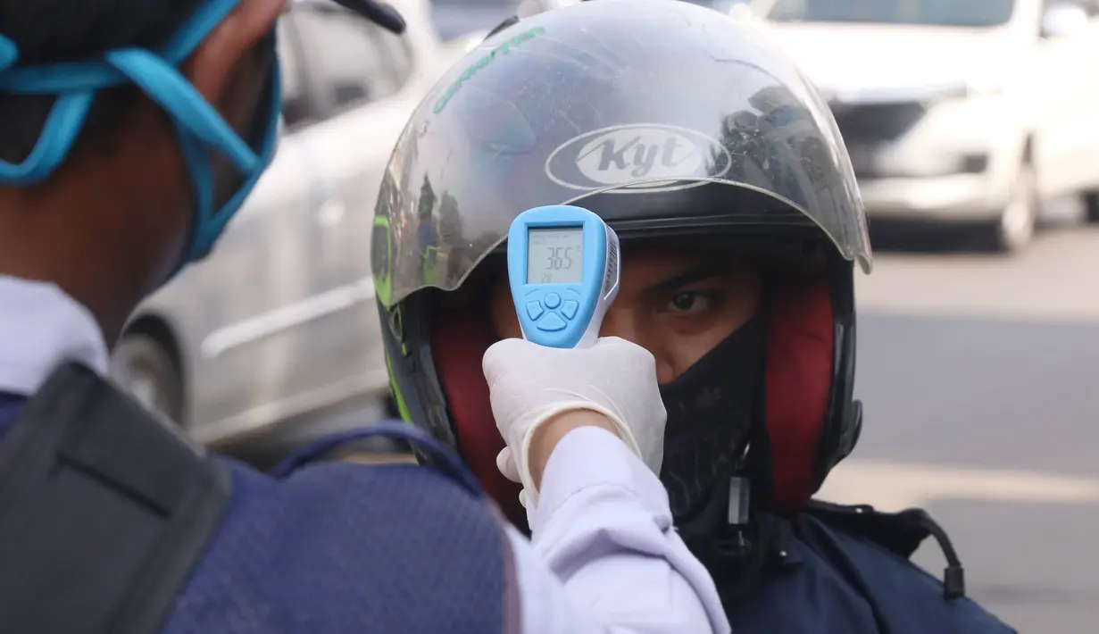 Petugas memeriksa suhu tubuh pengendara saat pelaksanaan Pembatasan Sosial Berskala Besar (PSBB) di kawasan Gading Serpong, Tangerang Selatan, Sabtu (18/4/2020). Pengukuran suhu tubuh tersebut merupakan cek point dari PSBB yang baru saja diberlakukan di Tangerang Raya. (Liputan6.com/Angga Yuniar)