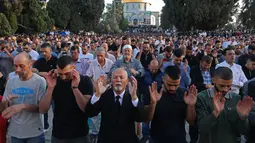 Umat Muslim melaksanakan sholat Idul Fitri di luar masjid Kubah Batu di kompleks masjid Al-Aqsa, Yerusalem Tua (13/5/2021).  Rentetan tembakan roket dari Gaza dan serangan udara Israel yang mematikan sebagai pembalasan. (AFP/Ahmad Gharabli)