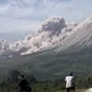 Orang-orang menyaksikan Gunung Sinabung memuntahkan material vulkanik saat meletus di Karo, Sumatera Utara, Kamis (11/3/2021). Gunung Sinabung erupsi dengan tinggi kolom 3.000 meter di atas puncak. (AP Photo/Binsar Bakkara)