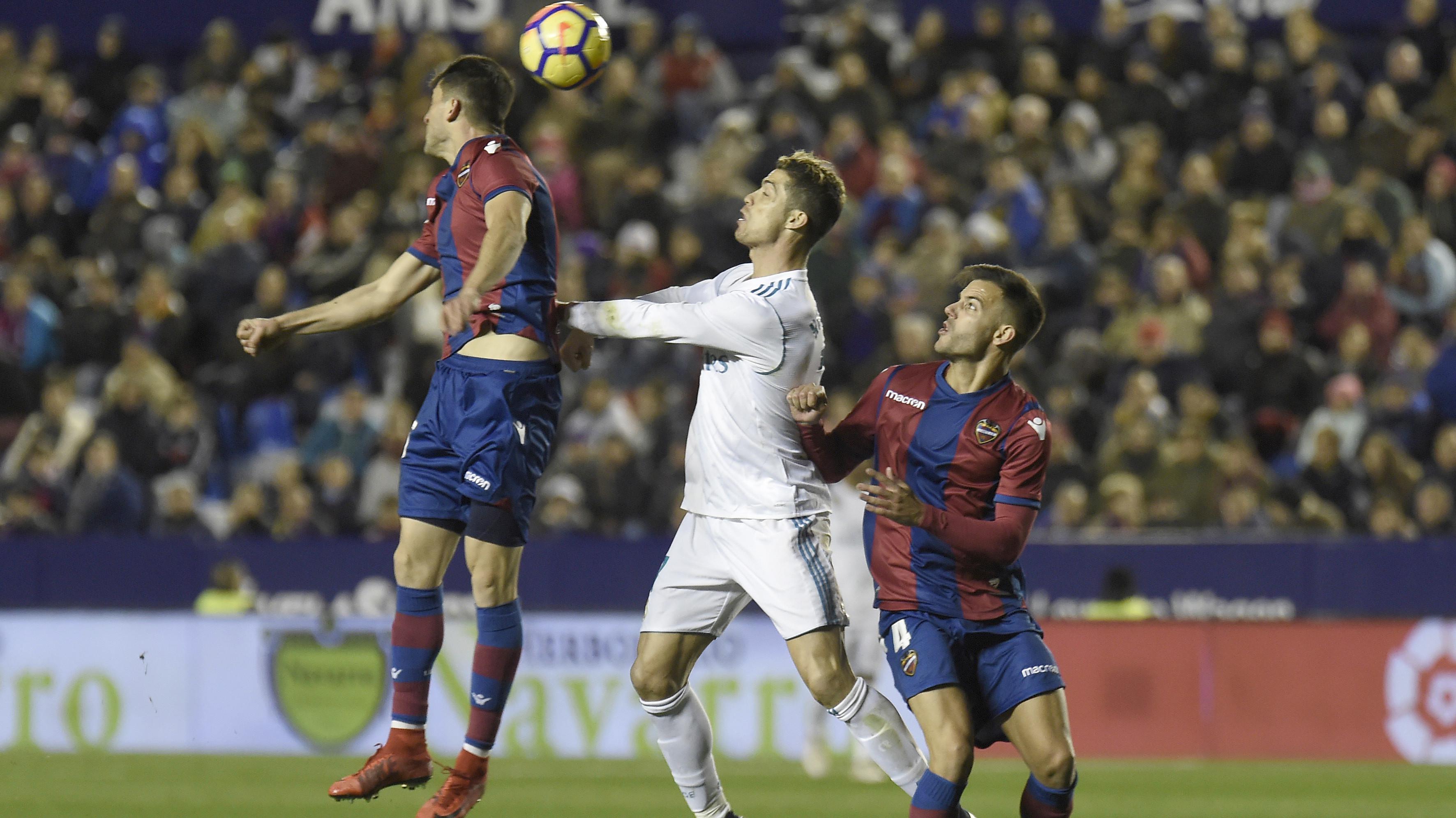 Cristiano Ronaldo (tengah) mencoba menggapai bola saat duel dengan dua pemain Levante  pada laga La Liga Santander di Ciutat de Valencia stadium, Valencia, Spanyol, (3/2/2018). Real Madrid bermain imbang 2-2. (AFP/Jose Jordan)