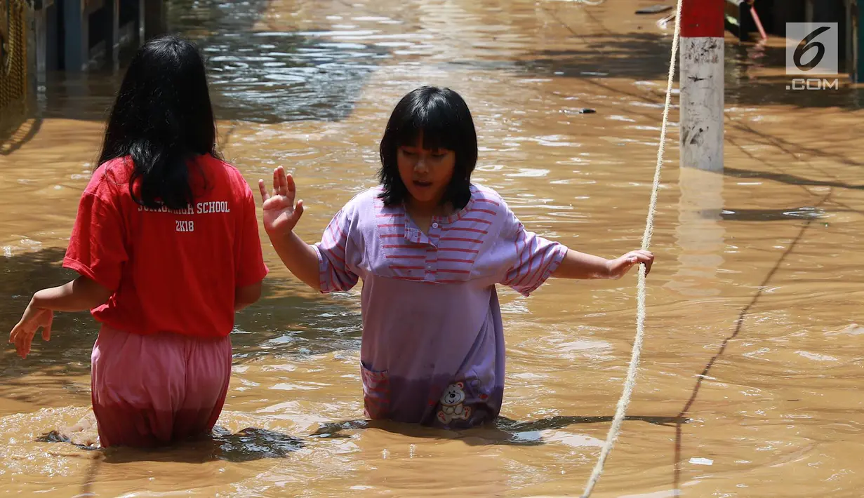 Dua anak melintasi banjir yang menggenangi kawasan Pejaten Timur, Jakarta, Jumat (26/4). Banjir yang berasal dari luapan Sungai Ciliwung tersebut merendam ratusan rumah warga hingga kedalaman lebih dari satu meter. (Liputan6.com/Immanuel Antonius)