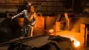 Seorang pekerja mengenakan pakaian pelindung mengambil cairan untuk membuat baja di Salzgitter, Jerman (22/3). Baja dibuat‎ dari hasil peleburan pasir besi, batu bara dan kapur dengan suhu di atas 1.000 derajat celciu‎s. (AP Photo / Markus Schreiber)