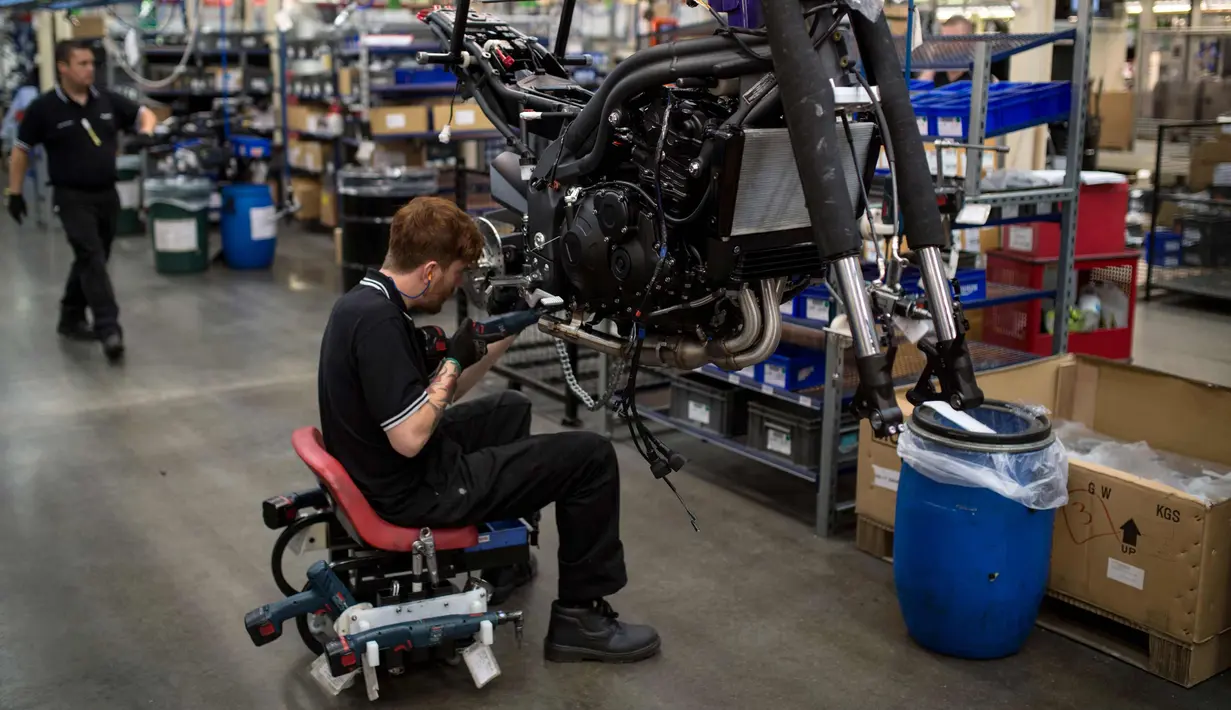 Pekerja mengencangkan baut bagian bawah sepeda motor Triumph di pabriknya di Hinckley, Inggris (2/10). Sejak 1902, Triumph dikenal dengan produksi motornya ber-cc besar. (AFP Photo/Oli Scarff)